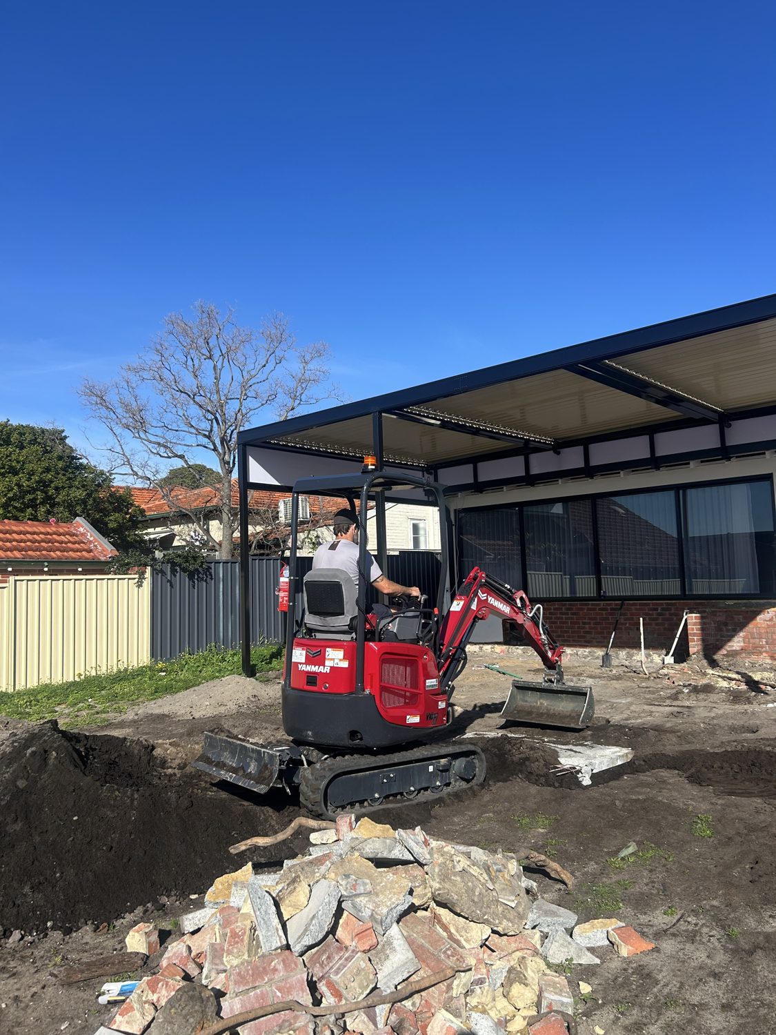 Yanmar mini excavator preparing the deck site next to the patio