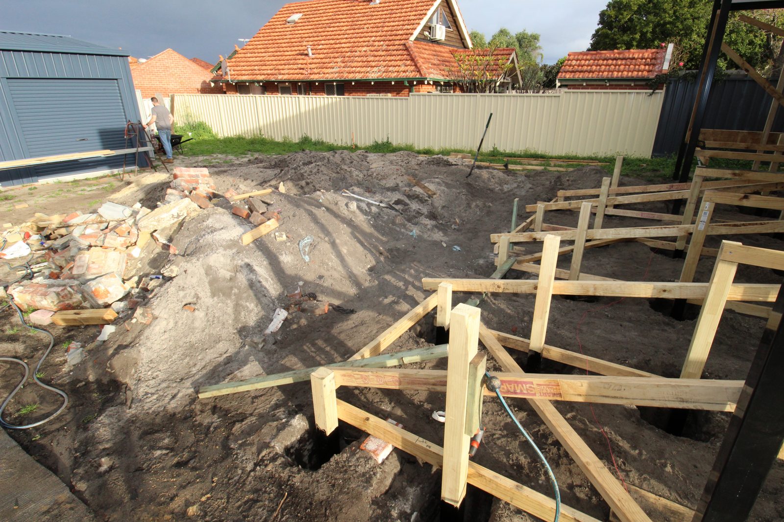 Deck subframe under construction with timber posts set in auger-bored footing holes in a Perth backyard