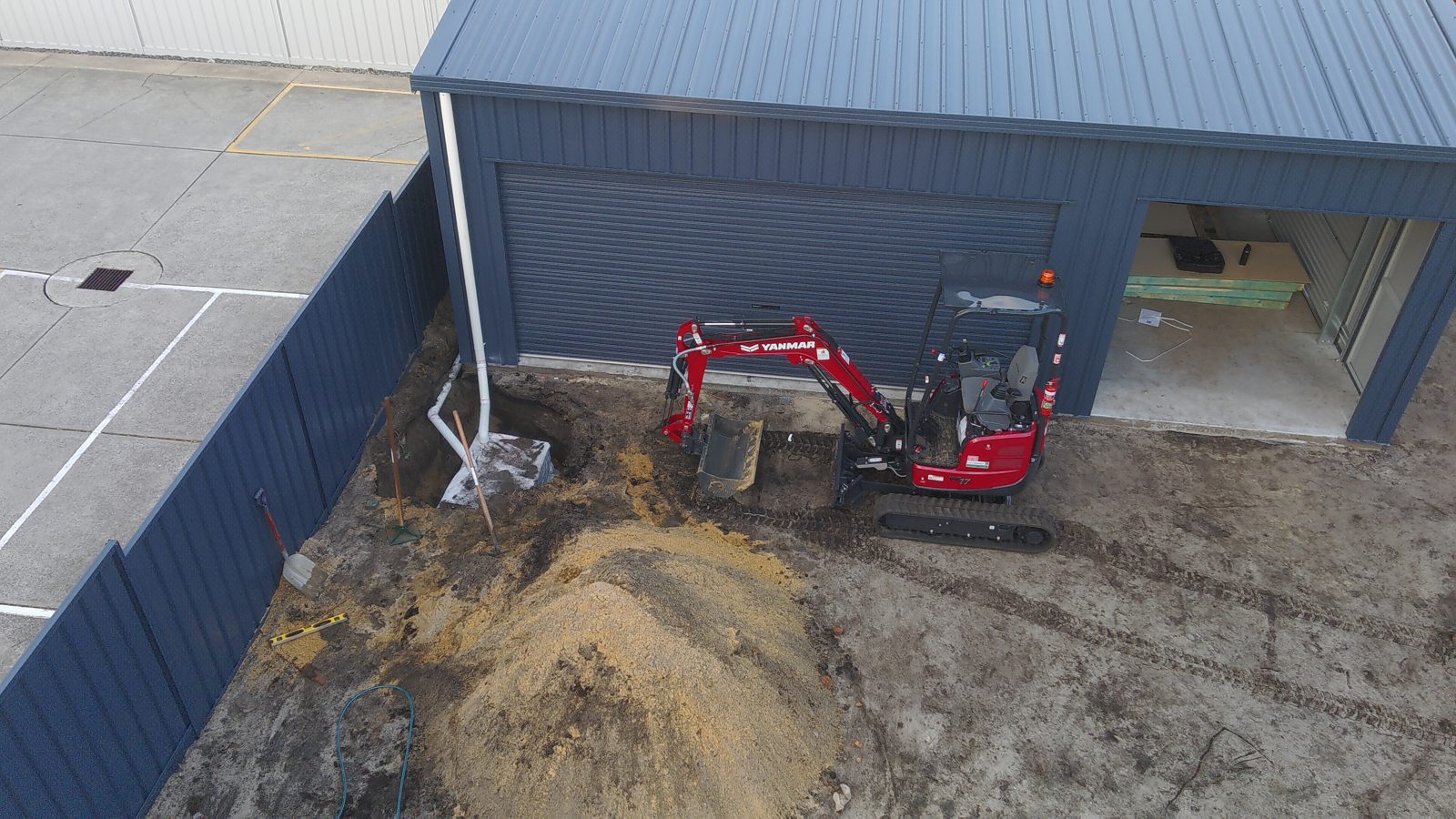 Drone view of a Yanmar ViO17-1 mini excavator digging a soakwell between a shed and a boundary fence in Perth