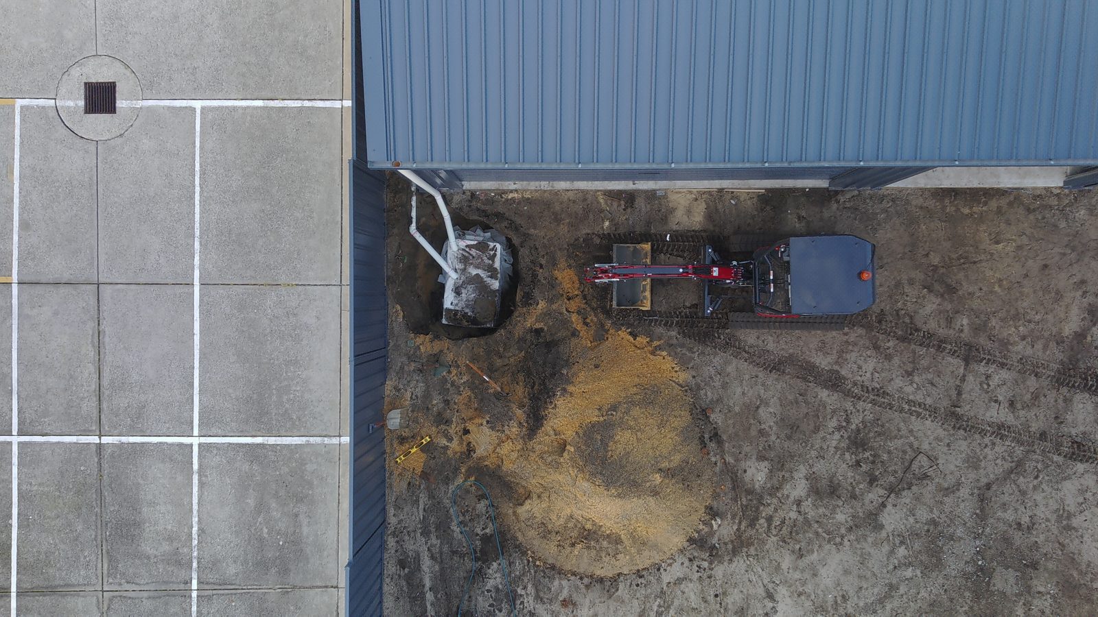 Top-down drone view of the soakwell trench and pipe run beside the shed
